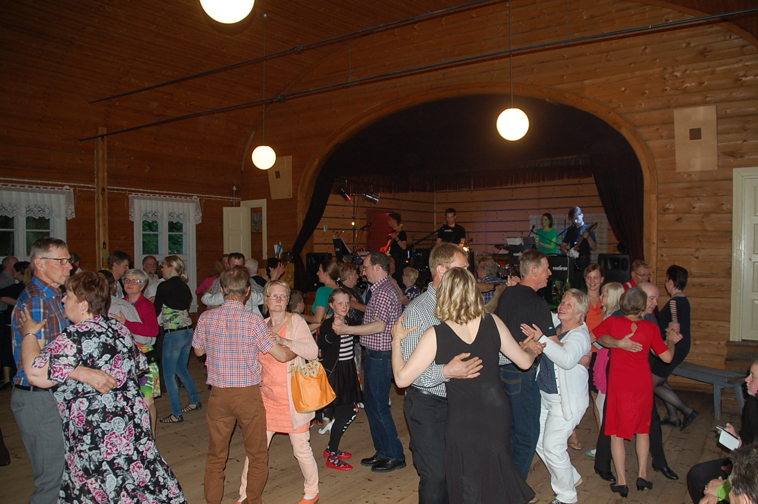 Paljon ihmisiä tanssimassa yhdessä seuratalon salissa.
