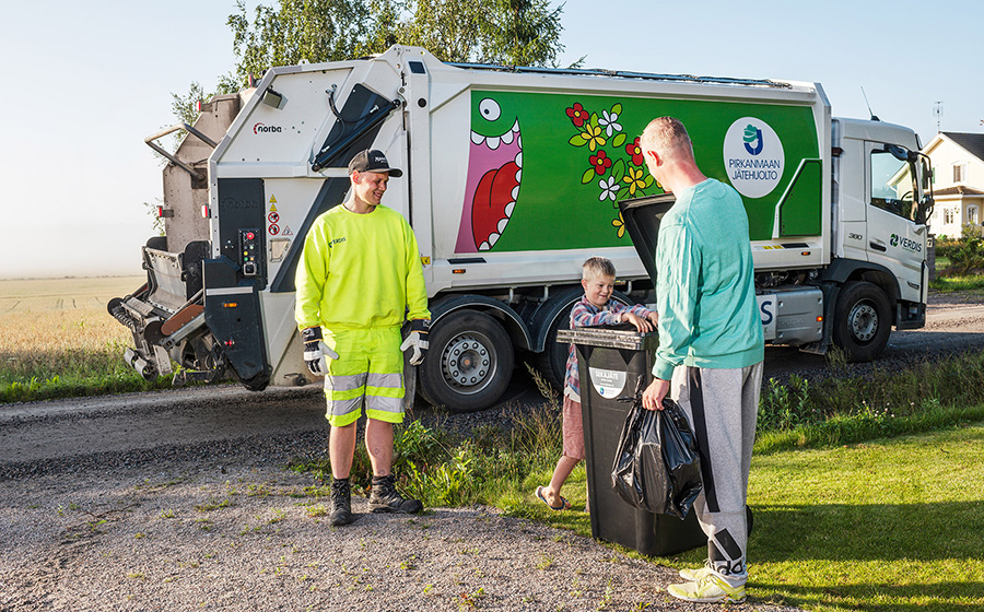 Kaksi aikuista ja lapsi kotipihan roskasäiliön luona, taustalla Pirkanmaan Jätehuollon auto.