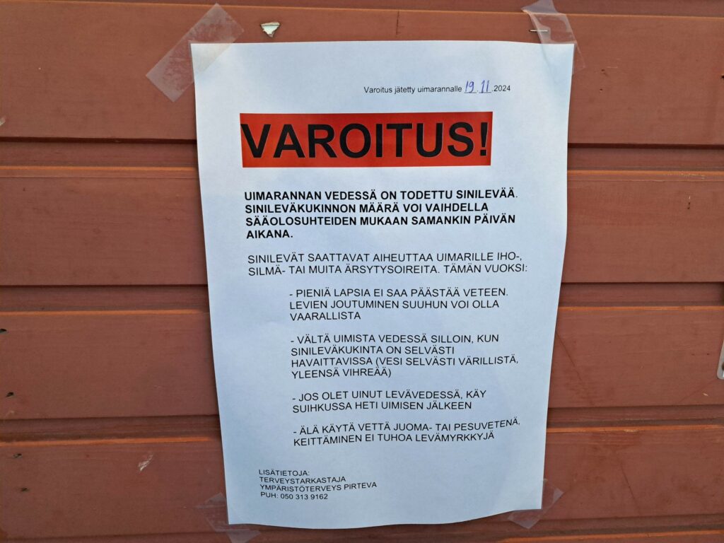 Tiedote ovessa, jossa kerrotaan, että uimarannan vedessä on havaittu sinilevää.